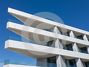 Tall White Building With Balconies Against Blue Sky