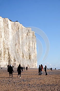 White chalk cliff face with pebble beach and lots of people walk