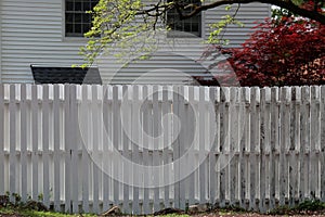 The tall white fence surrounds the house.