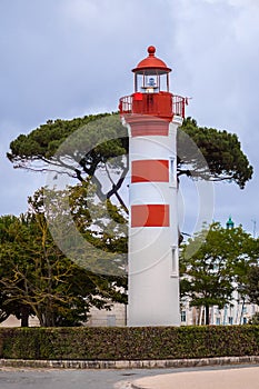 A tall, white and red lighthouse, is located in the picturesque port city