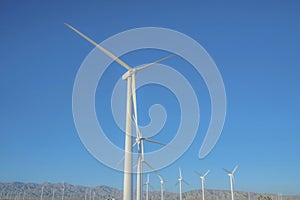 Tall white windmill with three blades that generates alternative energy