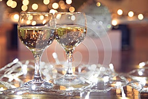 Tall wine glasses with bubbly drink for celebration toast wrapped in a Christmas light.