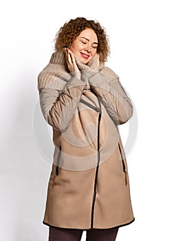 Tall woman in modern stylish beige sheepskin coat combined with textile sleeves and knitted scarf enjoying the warmth