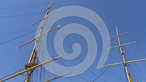The tall wooden masts of an ancient sailing ship against a clear blue sky. photo