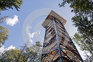 Tall wooden & metal lookout tower in forest. Sunny summer day