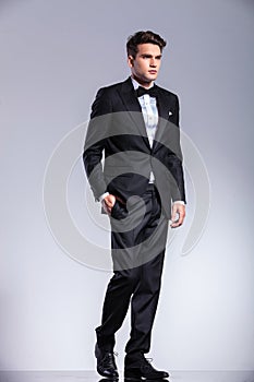 Tall young business man walking on studio background.