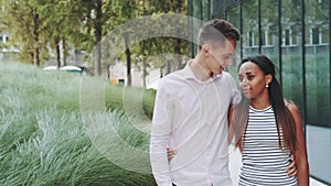 Tall young man kissing her african girlfriend while walking down the street