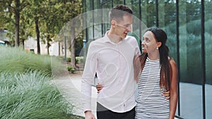 Tall young man kissing her african girlfriend while walking down the street