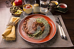 Tallarines verdes con chuleta de cerdo green pasta and pork chop Peruvian comfort food buffet traditional table photo