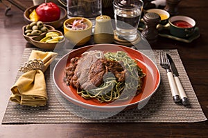 Tallarines verdes con chuleta de cerdo green pasta and pork chop Peruvian comfort food buffet traditional table photo