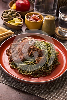 Tallarines verdes con chuleta de cerdo green pasta and pork chop Peruvian comfort food buffet traditional table photo