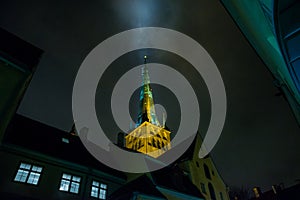 Tallinn, Estonia: Church of St. Olaf. The Church spire is illuminated. Bottom view. Old town with houses at night