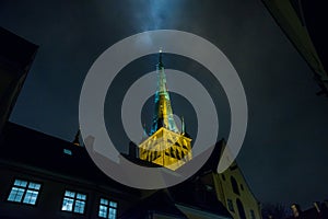 Tallinn, Estonia: Church of St. Olaf. The Church spire is illuminated. Bottom view. Old town with houses at night