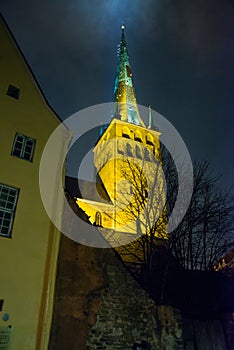 Tallinn, Estonia: Church of St. Olaf. The Church spire is illuminated. Bottom view. Old town with houses at night