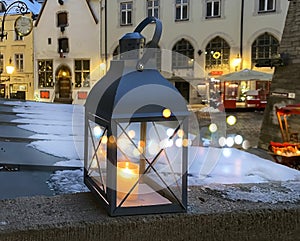 Tallinn Winter City Christmas lantern in yellow glass cup on snowy street in medieval Tallinn old town night blurred light