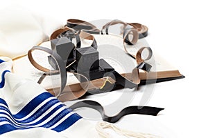 Tallit and tefillin and book on white background