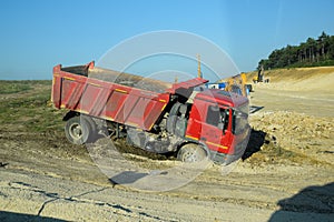 A dump truck kamaz got stuck in the mud on the side of the road