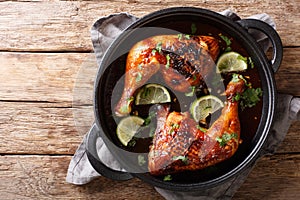 Tamarind chicken quarter leg with lime close-up in a frying pan. horizontal top view