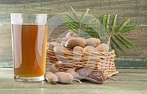 Tamarind juice in a glass surrounded by fresh ripe tamarinds - Tamarindus indica. White background photo