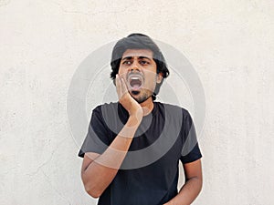 Tamil man wearing black tshirt touching cheeks with hands as he is suffering from toothache in right side. White