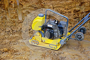 Tamping machine preparation of the ground by vibratory plate compactor in construction rammer in foundation pit for construction