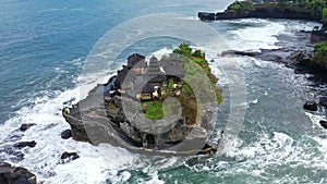 Tanah Lot Temple on the rock in Sea. Ancient hinduism place of worship. Sunlight. Aerial view. Bali, Indonesia