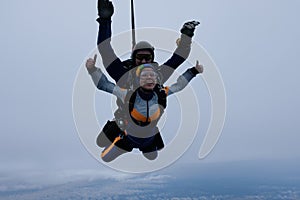 Tandem skydiving in the cloudy sky.