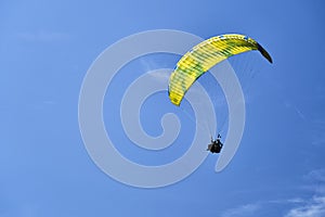 A tandem paraglider against a blue sky.