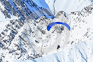 Tandem paragliders soaring against snowy mountain peak. Extreme prarglide winter flight