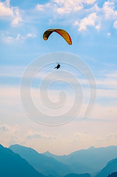 Tandem paragliding over Swiss Alps in sunset light. Photographed in Interlaken, Switzerland. Silhouettes of Swiss Alps and