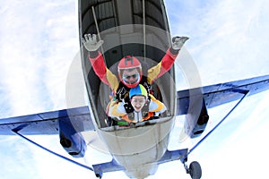Tandem skydiving. Active woman are jumping out of a plane. photo