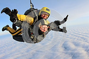 Tandem skydiving. Skydivers are flying above white clouds.