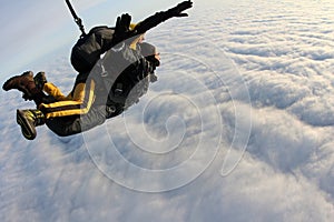 Tandem skydiving. Skydivers are flying above white clouds.