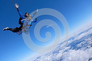 Tandem skydiving. Two guys are in the blue sky.