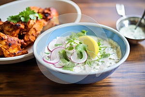 tandoori chicken served beside cucumber raita in a bowl