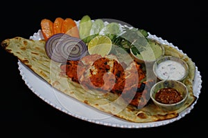 Tandoori chicken tikka with chutneys, vegetable salads and naan bread