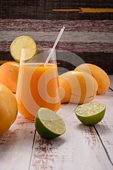 Tangerine juice with lime slice on white vintage wooden desktop with mangos