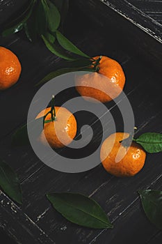 Tangerines on a black wooden stand. Photo with toning. Selective focus.