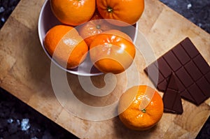 Tangerines with chocolate tablet on wooden board. Snack and breakfast