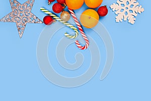 Tangerines, Christmas striped candy canes and snowflake on blue background. Free place for product or text. Christmas or new year