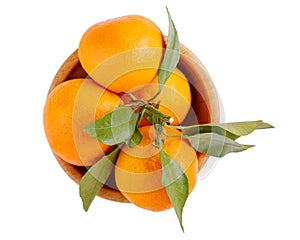 Tangerines, clementine citrus fruits with leaves in wooden bowl isolated on white. Top view