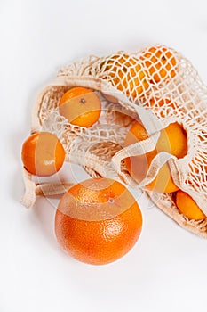 Tangerines, grapefruit fruits lie in a cotton eco-bag on a background. The concept of a healthy lifestyle and fres