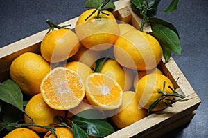 Tangerines with green leaves in a wooden box