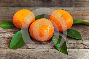 Tangerines with leaves on wooden background