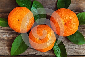 Tangerines with leaves on wooden background