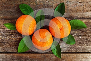 Tangerines with leaves on wooden background