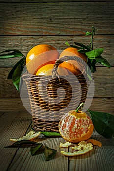 Tangerines with leaves in wooden basket on the table