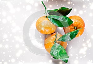 Tangerines, mandarines, clementines in winter holiday time, citrus fruits on plate with glowing snow and glitter on flatlay