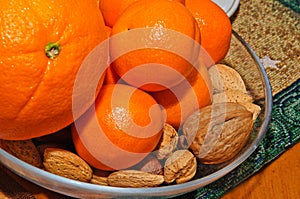 Tangerines, oranges and nuts in bowl.