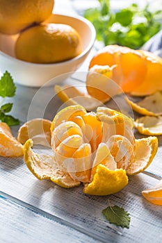 Tangerines with peel and mellisa herbs on table. Ripe fresh tropical fruit on wooden board